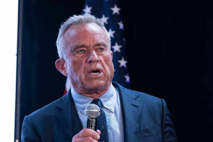 2456684675 Man holding microphone, speaking with American flag behind.