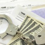 Handcuffs on tax forms with cash