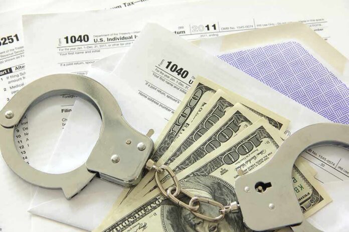 shutterstock_106939859 Handcuffs on tax forms with cash