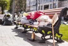 Person sleeping on a park bench with belongings
