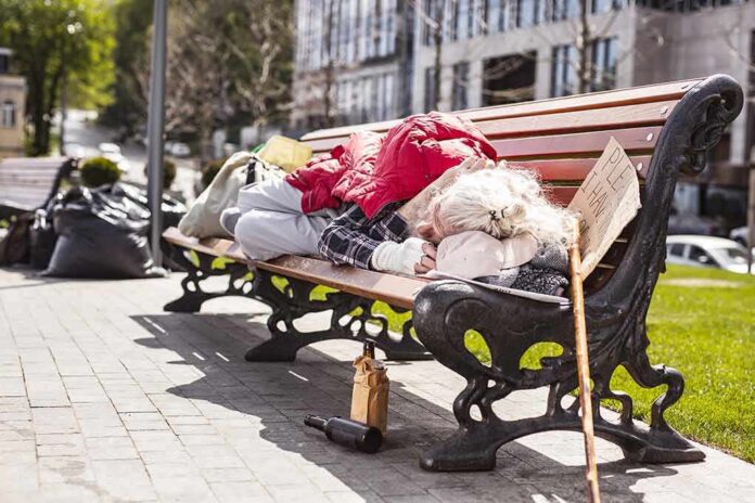 On the bench. Poor aged man lying on the bench while resting there Person sleeping on a park bench with belongings