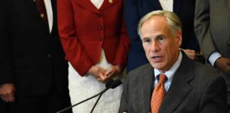 Governor’s Threat FREEZES Airport Basins man in suit speaking at a podium with a microphone