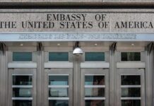 United States embassy entrance with metal doors and security camera