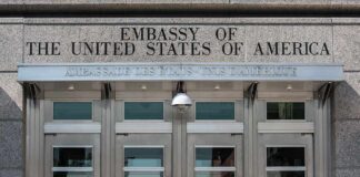 United States embassy entrance with metal doors and security camera