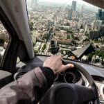 driver's hand on steering wheel over a tilted cityscape