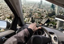 Flying Cars Are Coming To Florida driver's hand on steering wheel over a tilted cityscape