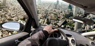Flying Cars Are Coming To Florida driver's hand on steering wheel over a tilted cityscape