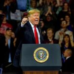 man speaking at a podium during a rally