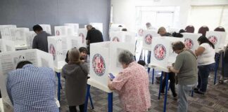 Voters fill out ballots at polling booths in a busy voting room