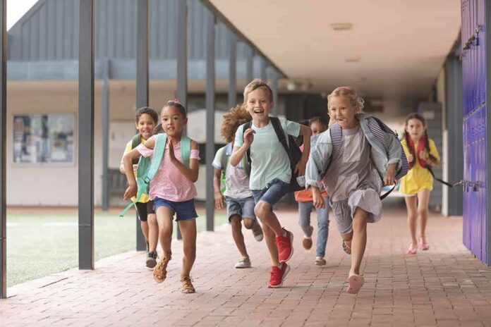 shutterstock_1352249762 Children running through a school hallway with backpacks