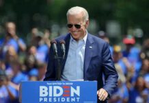 Man in sunglasses speaking at outdoor rally podium