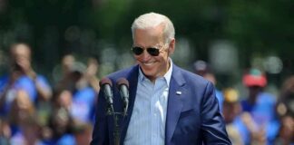 Man in sunglasses speaking at outdoor rally podium