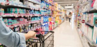 Shopper pushing a cart down a supermarket aisle