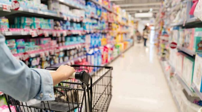Shopper pushing a cart down a supermarket aisle