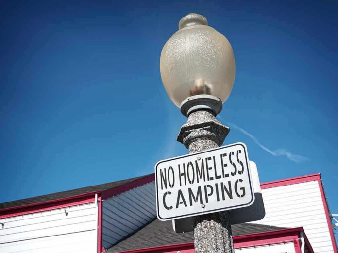 shutterstock_1592570302 Street lamp with a no camping sign against a blue sky