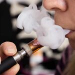 Close-up of a person vaping, exhaling smoke clouds