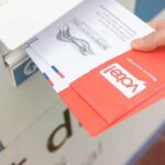 Hand dropping mail-in ballots into a drop box