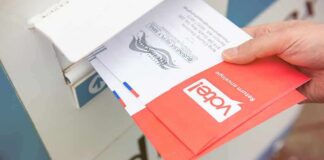 Trump Order Collides With Election Law Hand dropping mail-in ballots into a drop box
