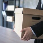 person in a suit carrying a cardboard storage box