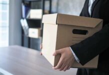 person in a suit carrying a cardboard storage box