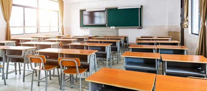 shutterstock_1717498237 Empty classroom with rows of desks and a chalkboard