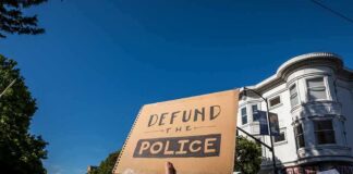 Democrat Denies Backing Police Defunding protesters holding signs at a street demonstration