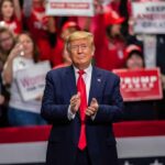 man in suit clapping at indoor rally