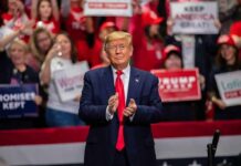 Donor Gates Lock Down Los Angeles man in suit clapping at indoor rally