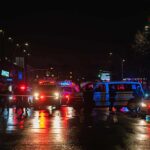 Nighttime police scene with flashing lights on a wet city street