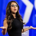 Woman speaking on stage with arms outstretched