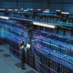 Technician with laptop in a large data center aisle