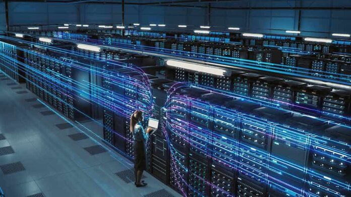 shutterstock_2204212039 Technician with laptop in a large data center aisle