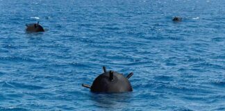 Naval sea mine floating in blue ocean water