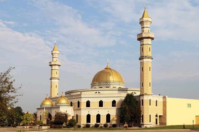 Mosque with golden dome and two tall minarets under a partly cloudy sky
