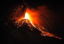 Lava Surge Triggers Midnight Evacuations Volcano erupting at night with glowing lava and ash plume