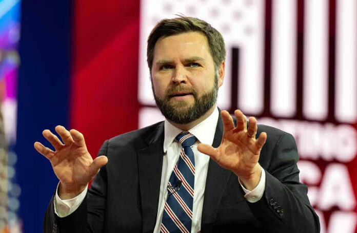 c0e4d3fd-3b50-4cd9-b02f-4e9933d13d92_2270811625.jpeg Man in suit speaking on stage with hands raised