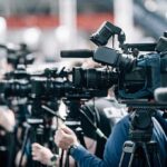 Broadcast cameras on tripods at a press event