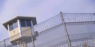 Prison watchtower behind barbed wire fencing