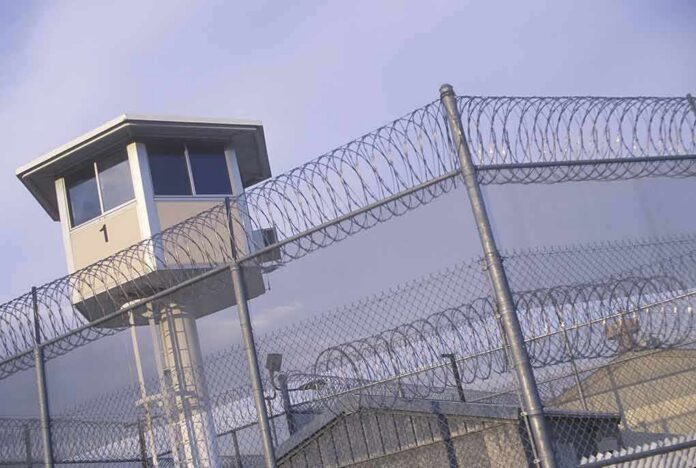 Prison watchtower behind barbed wire fencing