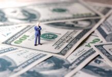 Billionaire Exodus Threat Rattles California Miniature businessman standing on US dollar bills