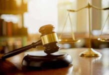Judge's gavel on a block with scales of justice in the background