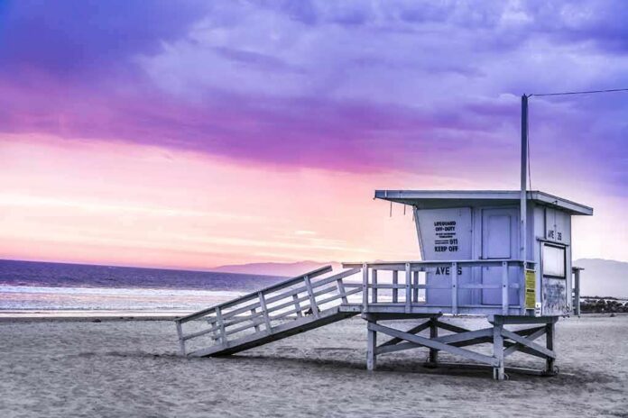 shutterstock_1089187769 Lifeguard tower on a sandy beach at sunset with colorful sky