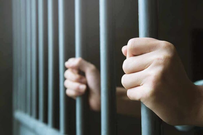 shutterstock_1115351336 hands gripping prison bars