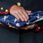 Uniformed person holding a folded American flag