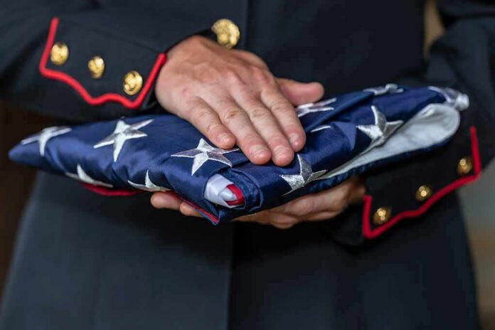 Uniformed person holding a folded American flag