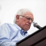 Bernie Sanders speaking at a podium with a microphone