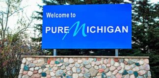 Hypocrisy Charge Erupts In Michigan Blue roadside sign on a stone base at a state border