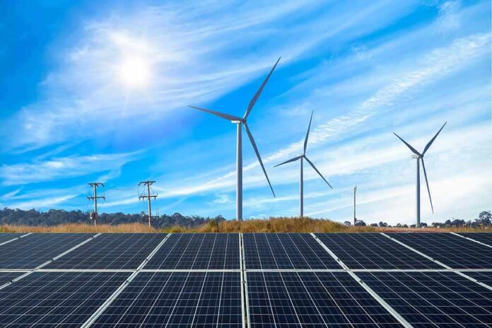 shutterstock_1671469138 Solar panels with wind turbines in a sunny landscape