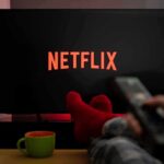 TV screen with Netflix logo and person holding remote