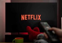 Bait-and-Switch Accusation Slams Netflix TV screen with Netflix logo and person holding remote
